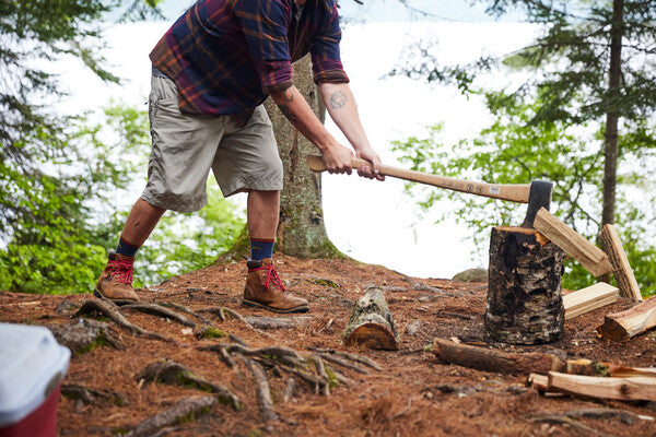Person chopping fire wood while wearing darn tough socks