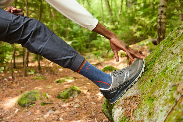 Hiker stretching their calf on the trail, feet wearing trail runners and the light hiker micro crew sock