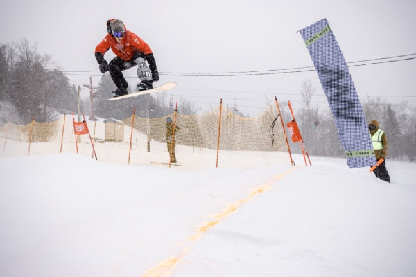 Pro Snowboarder Jake Blauvelt catching some air right before the finish line