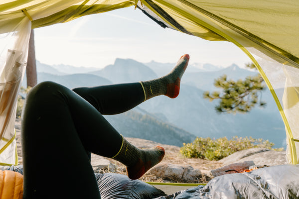 Model in a tent with a mountain view wearing Darn Tough Micro Crew Hiking Socks