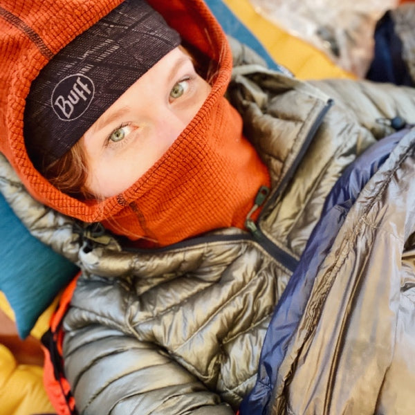 Alex all bundled up for cold weather camping with a hat, puffy, and sleeping bag