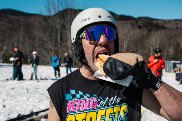 A skier taking a giant bite of grilled cheese, cooked by Darn Tough