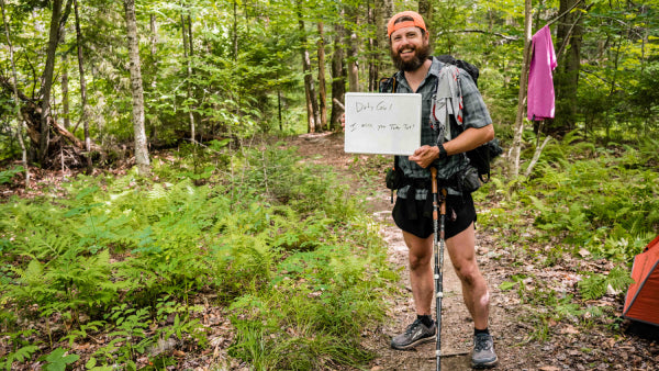 A thru hiker with the trail name Dirty Girl with a sign saying he misses his hiking partner