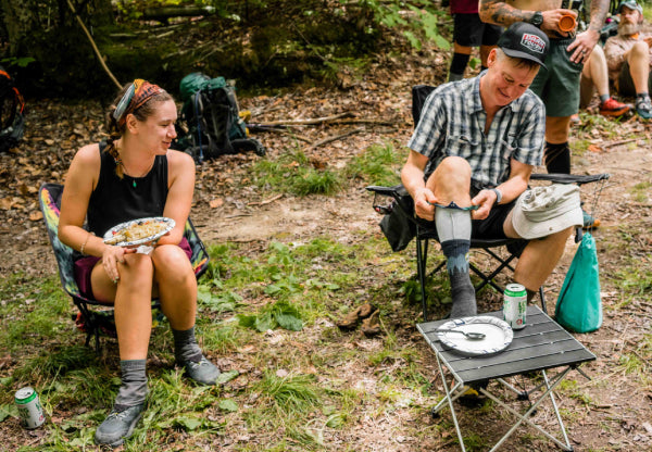 Two thru hikers seated eating local food and drinking local beer