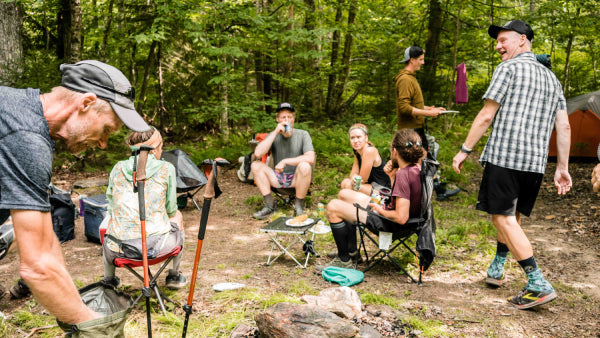 The trail magic scene, full of happy thru hikers on camp chairs with food and soda
