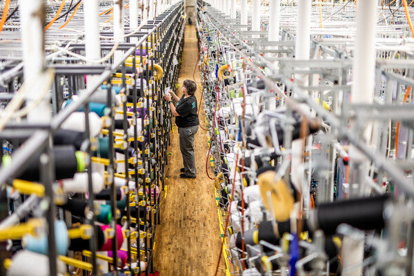 Woman checking on knitting machines at Darn Tough Mill in Vermont
