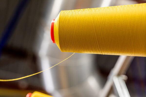 A cone of merino wool yarn with a thin thread coming off of it