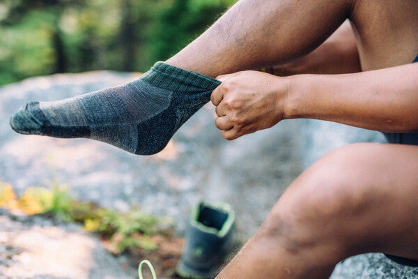 Person pulling on a pair of anti stink merino wool socks