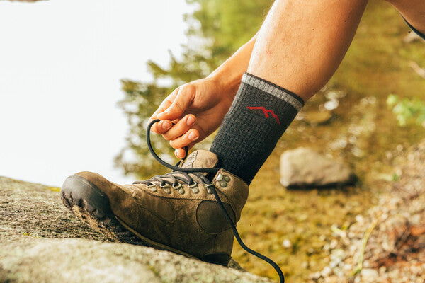 Hiker tying hiking boot laces wearing hiking boot socks