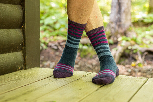 A woman's feet standing on a deck wearing the women's gatewood hiking boot socks