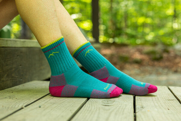Feet wearing non-wool hiking socks in bright blue with pops of pink