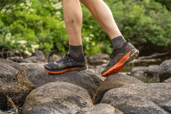 Hiker walking across rocks wearing hiking shoes and quarter socks