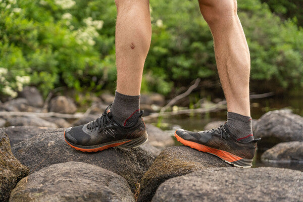 Closeup of feet walking on rocks in short merino wool socks with cushion, great for walks