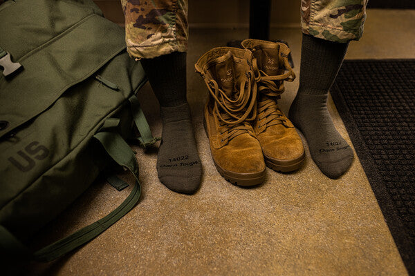 A pair of feet wearing darn tough tactical socks and combat fatigues