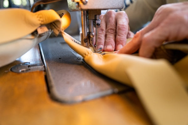 Hands sewing the goat leather together into gloves
