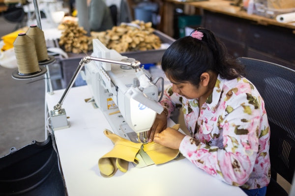 Woman at sewing machine working on a work glove