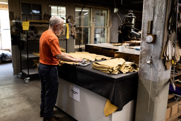 Employee examining leather hides to make sure they meet quality standards before cutting them