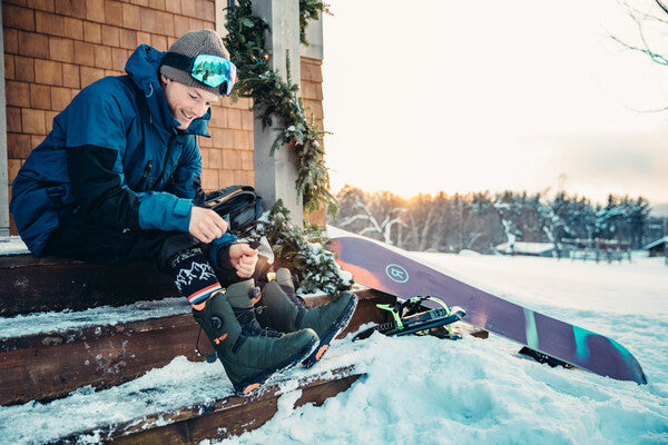 Jake Blauvelt pulling on his snowboard boots and darn tough wool socks