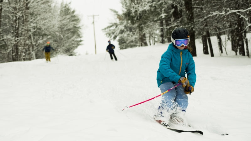 A small skier headed down the trails