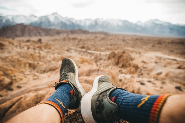 First person perspective shot of looking out past sock-clad feet at snow-capped mountains