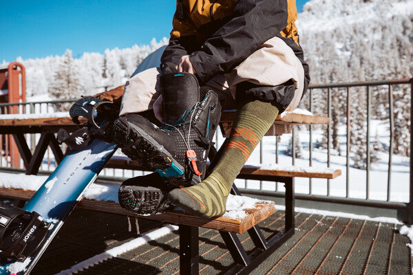 Snowboarder pulling boots on over Wool RFL Pennant socks