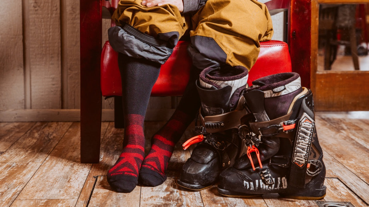 A skier in the lodge, boots off, and wearing merino wool socks for skiers