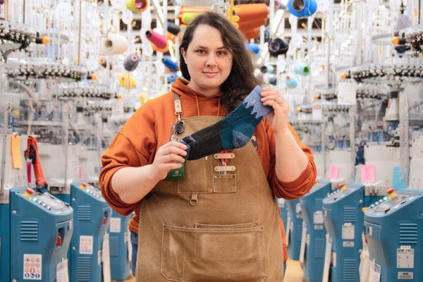 Jesse at the Mill holding her favorite sock gift idea, the Treeline women's hiking sock in blue