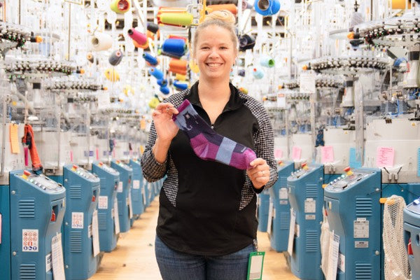 Pam holding up the Bear Town hiking socks in purple and blue, her favorite holiday sock gift idea