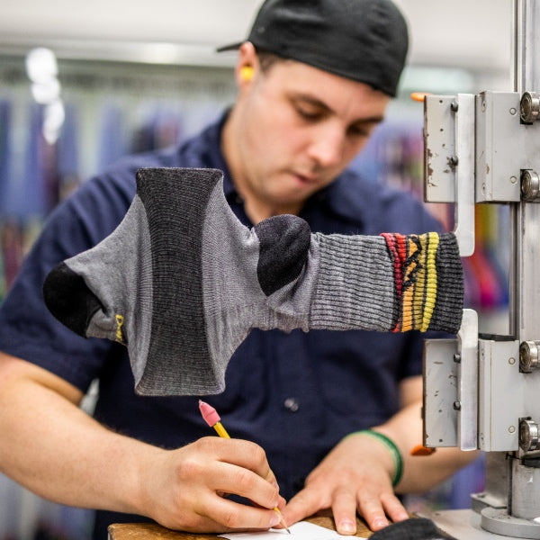 Darn Tough employee testing the stretch of a sock and taking notes