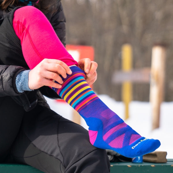 Nordic skier pulling on nordic socks, with a performance fit designed for nordic boots
