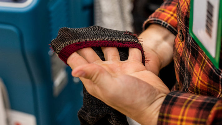 Hand holding a Darn Tough sock and stretching it gently, showing the flexibility