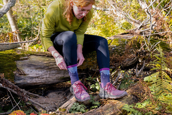 Hiker seated on leg looking at her Bear Town socks with an adorable bear on them