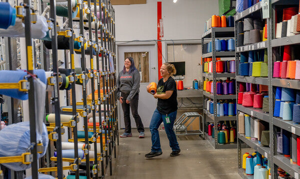 A person smiling and laughing surrounded by merino wool yarns