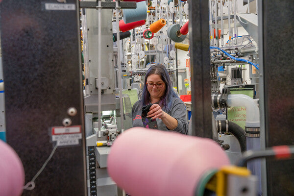 A woman smiling as she examines wool socks