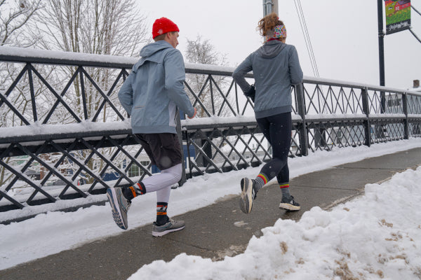 Two runners crossing a bridge as they run on a snowy winter day