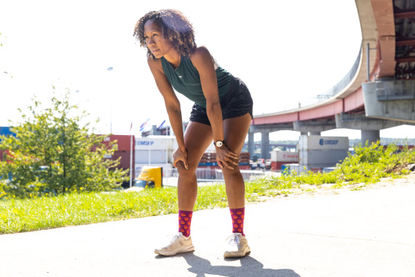 Runner wearing bright pink socks for running, paused to catch her breath