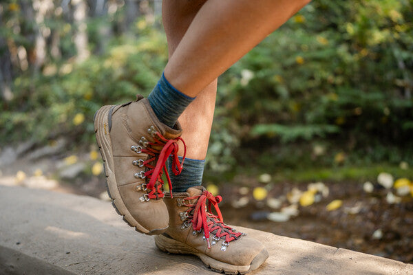 Feet in hiking boots and the women's light hiker micro crew socks in blue