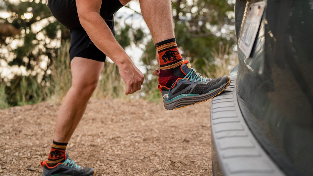 Person at trailhead putting on hiking shoes and merino wool socks to prevent blisters