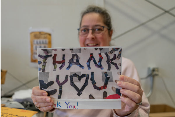 Andrea holding up a Thank You card she received