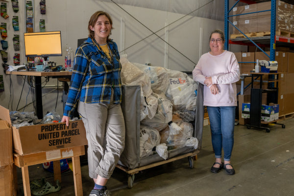 Andrea and Emily standing on either side of a cart full of warranty mail