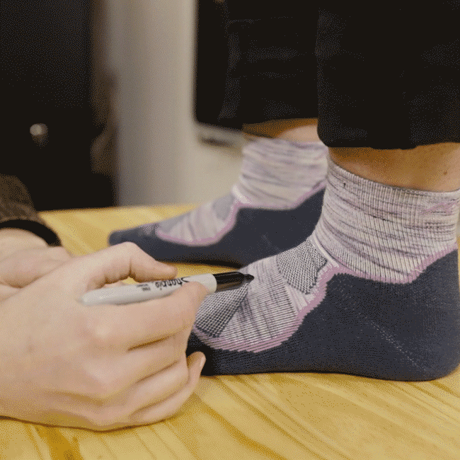 Darn Tough employees drawing on a sock with a marker during a fit session