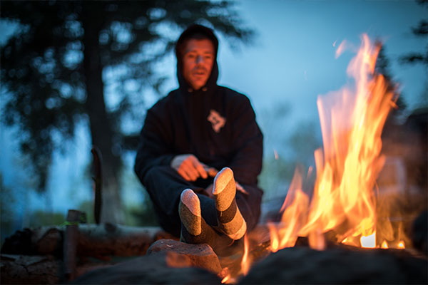 Man by campfire wearing warm comfortable merino wool socks