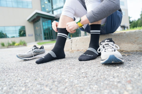 Runner sitting, pulling up Element Micro Crew socks and getting ready to put shoes on