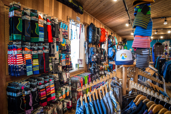 Rows of backpacks, hats, and Darn Tough socks in Alpenglow Sports store