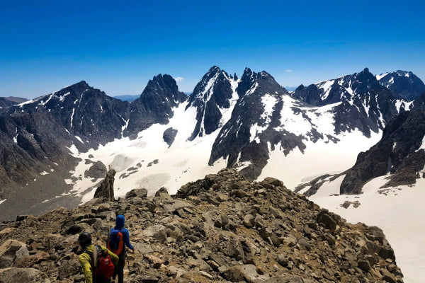 Two hikers headed down a steep rocky slope of Gannet Peak