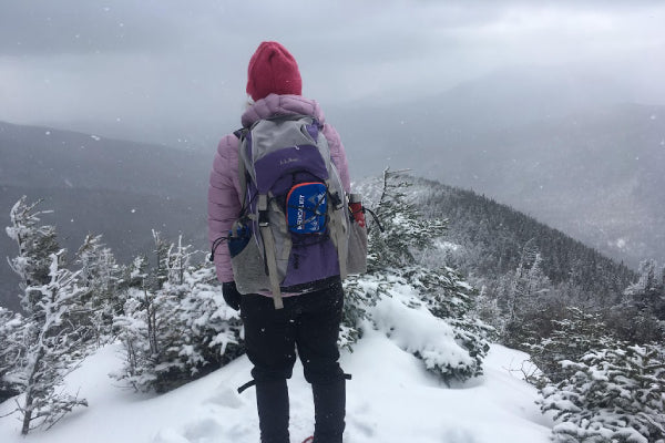 Hiker standing on the trail, above treeline, snowy landscape around
