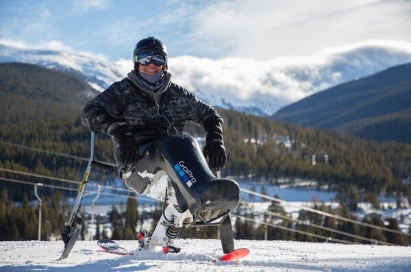 Trevor in his sit ski at the top of the mountain, beautiful views behind him