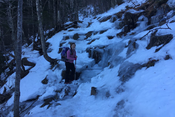 Hiker wearing microspikes and standing on frozen waterfall