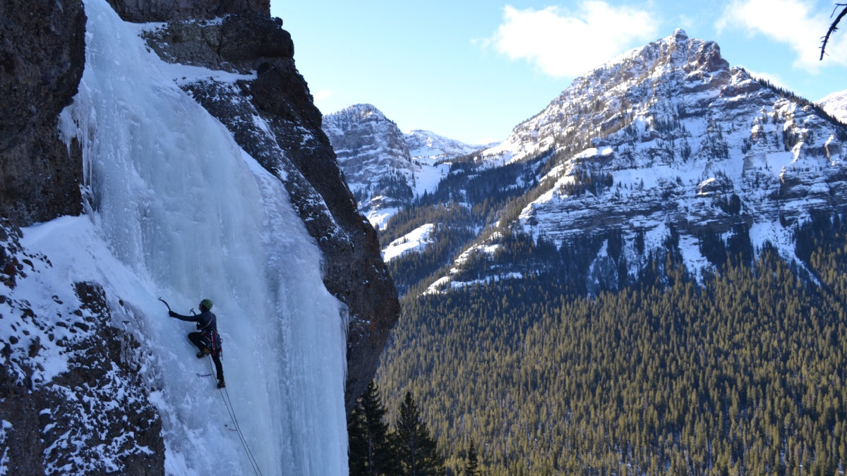 Ice climber partway up a dramatic frozen waterfall