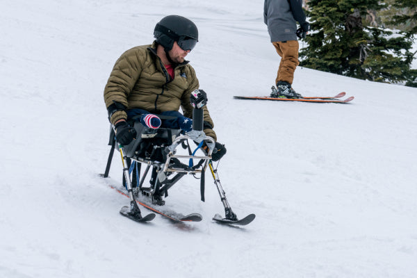 An amputee skiing down a hill on adaptive skis, having a blast